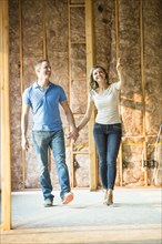 Caucasian couple walking in house under construction
