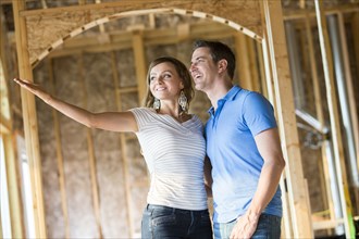 Caucasian couple admiring house under construction