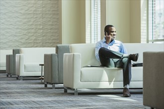 Black businessman talking on cell phone in office lobby