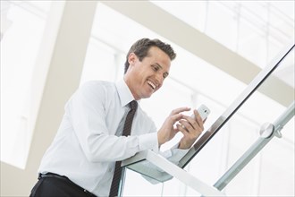 Caucasian businessman using cell phone on office staircase