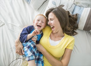Caucasian mother and son playing on bed