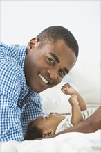 Father smiling with baby son on bed