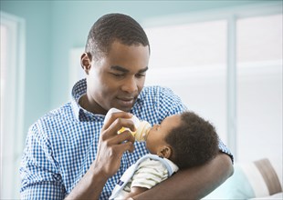 Father bottle feeding baby son
