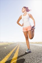 Caucasian runner stretching on remote road