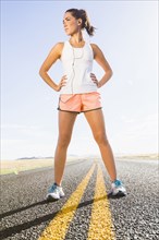 Caucasian runner standing on remote road