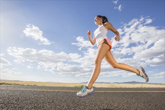 Low angle view of Caucasian woman running on remote road