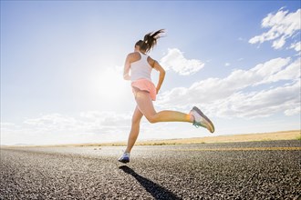 Low angle view of Caucasian woman running on remote road