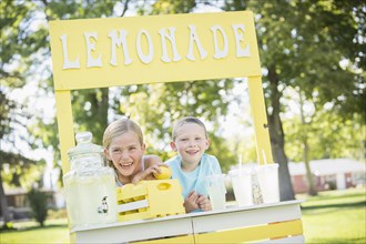 Caucasian brother and sister smiling at lemonade stand