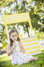 Caucasian girl drinking at lemonade stand