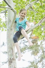Smiling Caucasian girl climbing tree outdoors