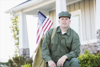 Caucasian soldier kneeling near house