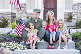 Caucasian soldier and family smiling together on front stoop