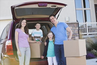 Caucasian family unpacking cardboard boxes from car