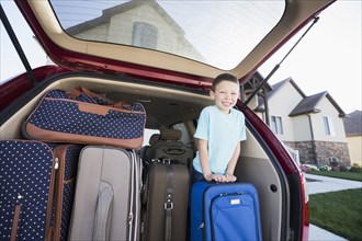 Caucasian boy smiling with suitcases in car