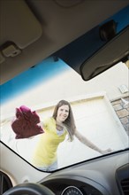 Caucasian woman washing car windshield