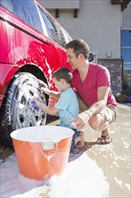 Caucasian father and son washing car in driveway
