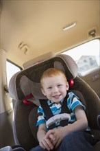 Caucasian boy smiling in car seat