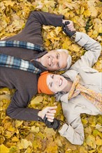 Older Caucasian couple smiling in autumn leaves