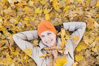 Older Caucasian woman smiling in autumn leaves