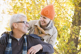 Older Caucasian couple smiling under autumn trees