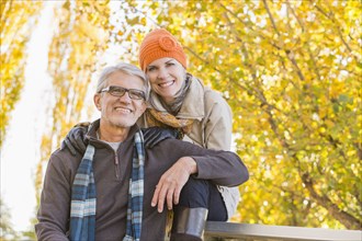 Older Caucasian couple smiling under autumn trees