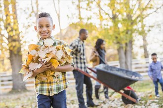 Boy holding pile of autumn leaves