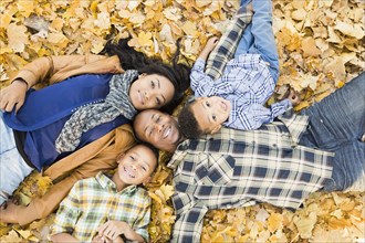 Family laying together in autumn leaves