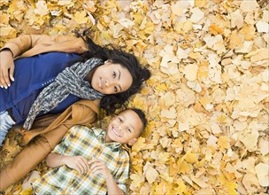 Mother and son laying together in autumn leaves