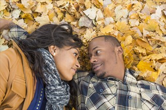 Black couple laying together in autumn leaves