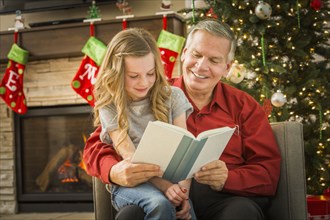 Caucasian grandfather reading to granddaughter at Christmas