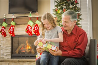 Caucasian grandfather opening Christmas gifts with granddaughter