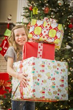 Caucasian girl holding pile of Christmas gifts