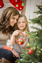 Caucasian mother and daughter decorating Christmas tree