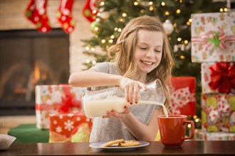 Caucasian girl leaving cookies and milk for Santa at Christmas