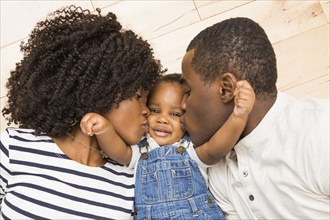 Black mother and father kissing cheeks of baby son