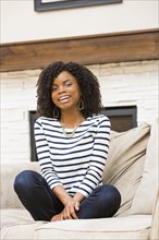 Black woman sitting cross-legged on sofa