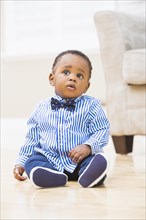 Black baby boy sitting on living room floor