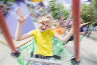 Caucasian girl riding roller coaster in amusement park