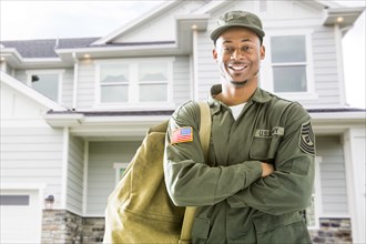 Black soldier standing outside house