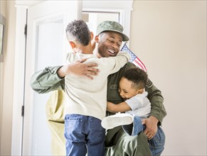 Returning soldier hugging children at door