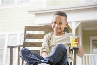 Black boy drinking orange juice in backyard