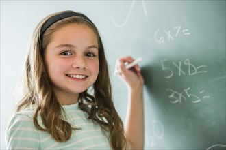 Caucasian girl doing math problems on chalkboard