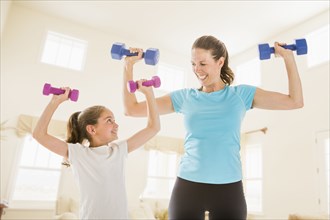 Caucasian mother and daughter lifting weights