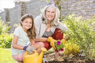 Caucasian grandmother and granddaughter gardening in backyard