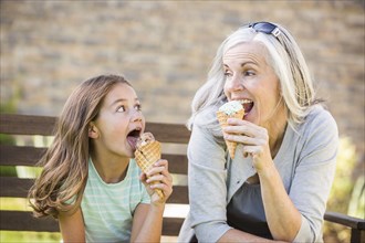 Caucasian grandmother and granddaughter eating ice cream