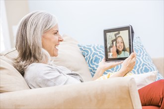 Caucasian grandmother videochatting with granddaughter on digital tablet