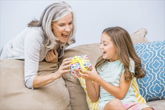 Caucasian girl giving grandmother a gift in living room