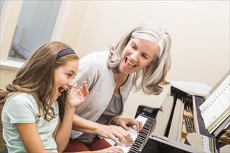 Caucasian grandmother and granddaughter playing piano
