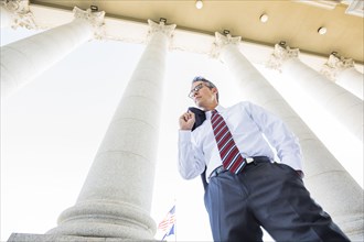 Low angle view of mixed race businessman standing under columns