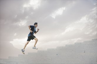 Mixed race man jogging on steps